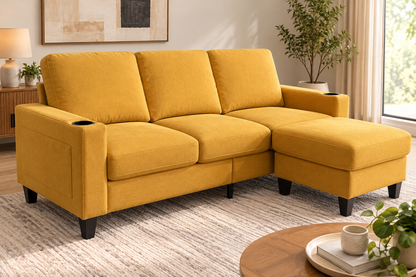 A mustard yellow fabric sectional sofa with a right-facing chaise lounge, shown in a bright, modern living room setting with a striped rug, a wooden coffee table, and a potted plant.